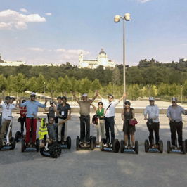 grupo grande montando en Segway con el Palacio Real de Madrid de fondo